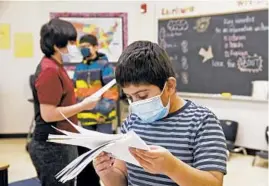  ??  ?? Alexis Duran, a fifth grader, goes over a writing assignment at O’Neal Elementary School in Elgin. Only about half of Elgin School District U-46 students returned for in-person classes so far.