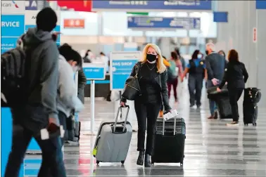  ?? NAM Y. HUH/AP PHOTO ?? A traveler wears a mask Sunday as she walks through O’Hare Internatio­nal Airport in Chicago.