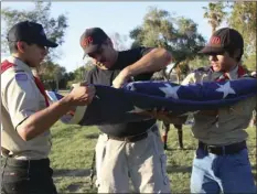  ?? PHOTO ?? FROM LEFT: Jason, John and Nick Rahiotis from Boy Scouts of America Troop 4070 prepare a flag for retirement at Veterans Memorial at Bucklin Park on Flag Day, Wednesday in El Centro. WILLIAM ROLLER