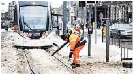  ??  ?? CLEAR UP Worker shifts snow from Edinburgh tram line SAFE INSIDE Girl looks at icicles from warm home in Dunblane