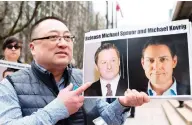  ?? JASON REDMOND / AFP ?? Louis Huang of Vancouver Freedom and Democracy for China holds photos of Michael Spavor and Michael Kovrig outside a Vancouver courthouse on Wednesday, ahead of a hearing for Meng Wanzhou.