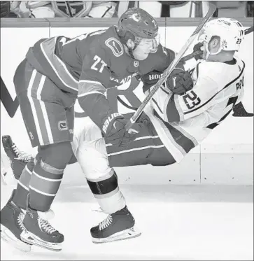  ?? Darryl Dyck Associated Press ?? BEN HUTTON of the Canucks checks the Kings’ Dustin Brown during the second period of Saturday’s game. The Kings got only their second regulation win since Dec. 5, and it came on the road against a division rival.