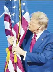  ?? AP ?? Republican presidenti­al candidate Donald Trump hugs and kisses the US flag during a campaign rally in Maryland on Saturday.