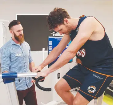  ??  ?? TESTING TIMES: CQ University exercise and sports science lecturer Joshua Guy runs Cairns Taipans co-captain Alex Loughton through a static bicycle linked to precision analysis. Picture: BRENDAN RADKE