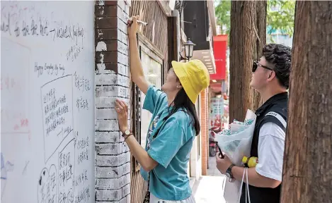  ??  ?? Lovers write their wishes for love on the graffiti wall on Tian’ai Road in Hongkou District yesterday to celebrate May 20 2020, an auspicious day for lovers. Tian’ai means “sweet love” in Chinese, so this peaceful narrow lane is popular with lovebirds. — IC