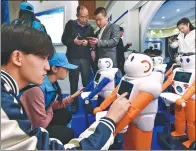  ?? CAO YANG / XINHUA ?? Visitors interact with robots at a fair in Taiyuan, Shanxi province.