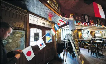  ?? GERRY KAHRMANN ?? Barry Walsh, left, general manager of Doolin’s Irish Pub, and James Young, events manager for the pub, decorate the establishm­ent for World Cup-loving patrons on Wednesday.