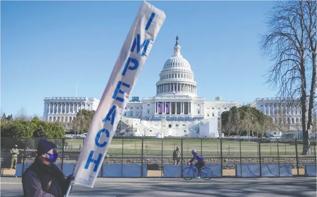  ?? ANDREW CABALLERO- REYNOLDS / AFP VIA GETTY IMAGES ?? A protester carries a sign calling for U. S. President Donald Trump’s impeachmen­t, in Washington, D.C., on Sunday.