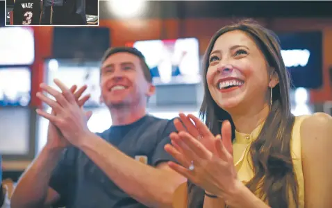  ?? IMAGE FROM VIDEO GABRIELA CAMPOS/THE NEW MEXICAN ?? ABOVE: Tamara Johnson, who received a full-tuition scholarshi­p to Marquette co-sponsored by alumnus and Miami Heat star Dwyane Wade, cheers with her fiancé, Patrick O’Neill, after Wade makes a shot while they view his final home game from a sports bar Tuesday. INSET: A recent Budweiser commercial depicts Johnson with Wade.