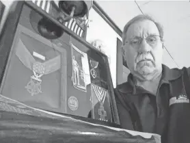  ?? PROVIDED BY JOHN EDWARDS ?? John Edwards of Plainville, Mass., holds a shadow box containing medals awarded to his uncle, Cumberland native Lt. Robert Waugh, for his service in World War II. The Medal of Honor is at left, and the Rhode Island Cross is at bottom right.