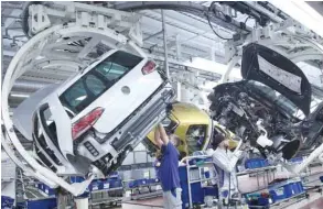  ?? — AFP ?? Employees of German carmaker Volkswagen (VW) work on a Golf VII car at an assembly line at VW plant in Wolfsburg, central Germany.