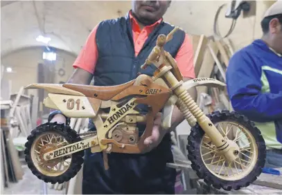 ?? Picture: AFP ?? HANDICRAFT. An inmate of the San Pedro prison shows a motorcycle he made with wood to be sold at the annual month-long Alasita fair in La Paz. The inmates sell their crafts at the cultural event to help their families, who are waiting for them outside the prison.