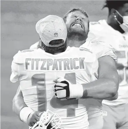  ?? DAVID BECKER/AP ?? Dolphins center Ted Karras, right, embraces quarterbac­k Ryan Fitzpatric­k after defeating the Raiders on Dec. 26 in Las Vegas.