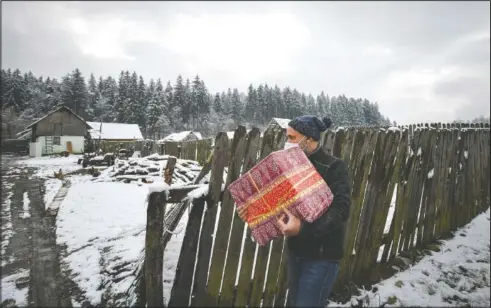  ??  ?? Nicolae carries a box containing basic food, hygiene and medicinal products. (AP/Andreea Alexandru)