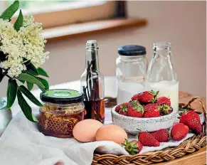  ??  ?? The simple life... a farm kitchen bench with a bowl of freshly picked strawberri­es, a vase of elderflowe­rs, farm fresh eggs, and a jug of cream from the house cow.
