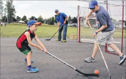  ?? MILLICENT MCKAY/JOURNAL PIONEER ?? Dylan Thomas, 6, goes head to head with his father Cory, as John Chaisson guards the net during a game of ball hockey at the recent block party arranged by the city to promote community spirit and develop bonds with neighbours.