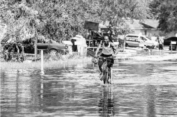  ?? PHOTOS BY AILEEN PERILLA/STAFF PHOTOGRAPH­ER ?? A man rides his bike Tuesday through a flooded Orlo Vista neighborho­od. Mayor Teresa Jacobs said the government earmarked counties that would be impacted by Irma but didn’t anticipate Central Florida would suffer significan­t damages.