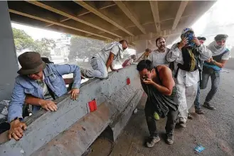  ?? Ariana Cubillos / Associated Press ?? Demonstrat­ors run from tear gas and police during anti-government protests Wednesday in Caracas, Venezuela. Opponents of President Nicolas Maduro flooded the streets of the capital.