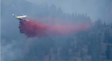  ?? JONATHAN HAYWARD/THE CANADIAN PRESS FILE PHOTO ?? An air tanker drops fire retardant on a B.C. hillside in 2014. Aaron Williams recounts the story of a fire season in a new memoir.