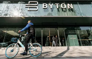  ??  ?? A cyclist is passing by the BYTON Place showroom in Shanghai.