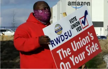  ?? Jay Reeves/Associated Press ?? Michael Foster of the Retail, Wholesale and Department Store Union holds a sign outside an Amazon facility where labor is trying to organize workers.