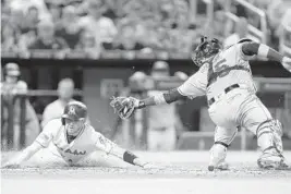  ?? MICHAEL REAVES/GETTY IMAGES ?? Marlins shortstop JT Riddle slides past Rays catcher Jesus Sucre to score in the sixth inning of Wednesday’s game at Marlins Park in Miami.