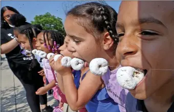  ?? (STUART CAHILL — BOSTON HERALD ?? Bryan Durtegomes, (R) 7, races to eat his donut as the Salvation Army Kroc Community Center celebrates National Donut Day.