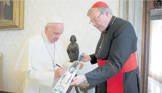  ??  ?? Juntos. El Papa, en una imagen de octubre de 2015, firma un bate de cricket que sostiene el cardenal Pell, hoy en medio de la tormenta.