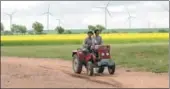  ?? SU WEIZHONG / FOR CHINA DAILY ?? Two farmers on a tractor pass through a wind power farm in Inner