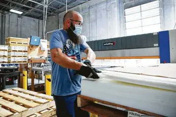  ?? Elizabeth Conley / Staff photograph­er ?? Jason Scott, warehouse manager for Profession­al Plastics, cuts acrylic at the Stafford warehouse to use in the making of clear plastic barriers.