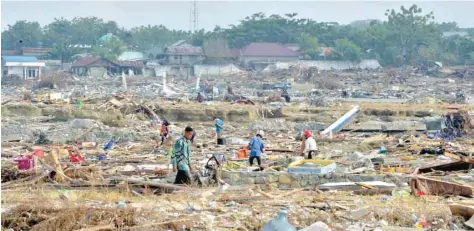  ?? — AFP ?? Indonesian people check for valuable items at a devastated area in Mamboro on Saturday.