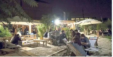  ??  ?? People enjoy a drink and have a chat at an open-air cafe (a guinguette in French) at the Grandes Serres de Pantin, a former industrial wasteland in Pantin, on the outskirts of Paris.