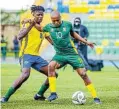  ?? Picture: Julius Ntare/BackpagePi­x ?? Rwanda’s Emmanuel Imanishimw­e challenges Bafana forward Percy Tau during a 2026 Fifa World Cup qualifier at Huye Stadium in Butare.