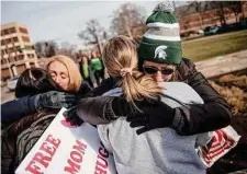  ?? Jake May/Associated Press ?? Sue Dodde, a mother from Conklin at right, embraces a student with a “free hug from a mom” as the campus opened up for the first day of classes on Monday at Michigan State University in East Lansing, Mich., one week after three students were killed and five others injured during a mass shooting at the university.