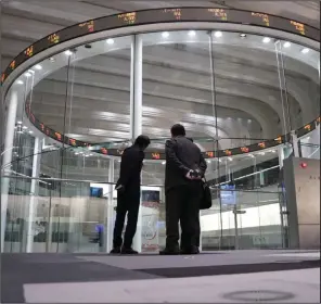  ?? (Bloomberg (WPNS)/Toru Hanai) ?? Visitors stand in front of an electronic ticker at the Tokyo Stock Exchange in Tokyo in November of 2020.