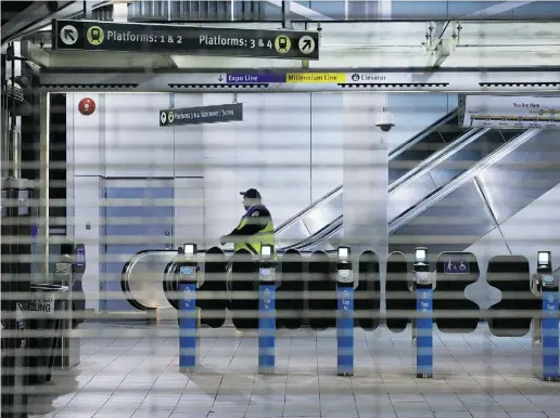  ?? THE CANADIAN PRESS / Da rryl Dyck ?? A worker is seen behind the locked gates of a Vancouver SkyTrain station after the system was shut down to check for damage to elevated guideways in the early hours of Wednesday after an earthquake struck the West Coast late Tuesday.