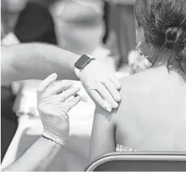  ?? VASHON JORDAN JR./CHICAGO TRIBUNE ?? Sergio Sida-Valdez, from Alivio Medical Center, administer­s a Pfizer COVID-19 vaccine Aug. 8 to Maria Beltran at a Chicago Department of Public Health vaccinatio­n site at Swap-O-Rama in Chicago.