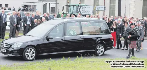  ?? MARK JAMIESON ?? A piper accompanie­s the funeral cortege of Wilson Atchison at Ballyrasha­ne Presbyteri­an Church