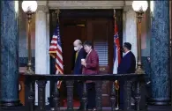  ?? (AP/Rogelio V. Solis) ?? Mississipp­i State basketball coach Ben Howland (masked at left) and football coach Mike Leach pass the Mississipp­i state flag Thursday at the state Capitol in Jackson as they joined in lobbying for a new state flag.