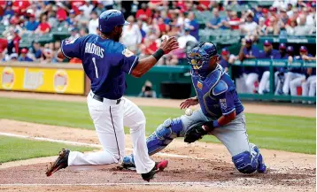  ?? Associated Press ?? n RANGERS 5, ROYALS 3. Texas Rangers’ Elvis Andrus scores a run as Kansas City Royals catcher Salvador Perez fails to control the ball Saturday during the second inning of an exhibition game in Arlington, Texas.