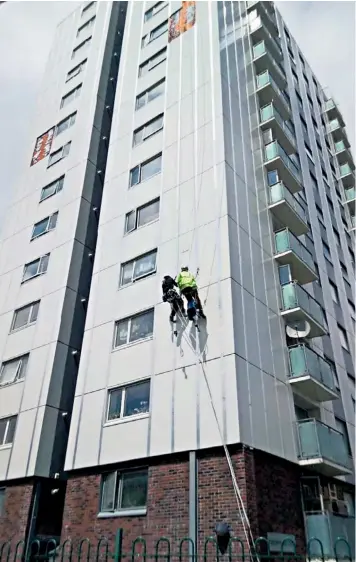  ??  ?? Workers abseil down Harpenmead Point building on the Granville Estate, north London, yesterday