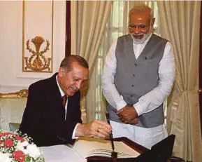  ?? AP PIC ?? Indian Prime Minister Narendra Modi looking on as Turkish President Recep Tayyip Erdogan signs a visitor’s book in New Delhi during his two-day visit to India recently.