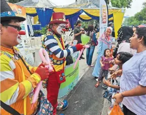  ?? ?? (right) Nirmeshini, 34, and her daughter akshaya are excited to see awang the clown group entertaini­ng visitors at the bazaar.