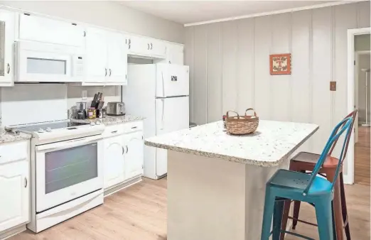  ?? ?? The previously remodeled all-white kitchen features an island that provides additional storage and seating.