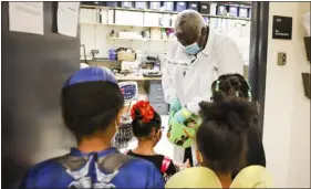  ?? MICHAEL CIAGLO — SPECIAL TO THE DENVER POST ?? National Jewish Health bioenginee­ring affiliate Brian Harris hands out candy to Morgridge Academy students as they trick-or-treat around the non-patient-occupied buildings at the National Jewish Health campus in Denver in October 2021.