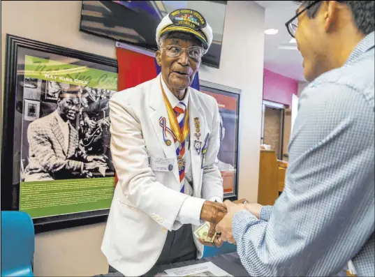  ?? L.E. Baskow Las Vegas Review-Journal @Left_Eye_Images ?? World War II, Korean War and Vietnam War veteran Arby Hambric sells one of his signed books to Ryota Naito during the Juneteenth Jazz, Arts and Spoken Word Celebratio­n on Saturday at the West Las Vegas Library.