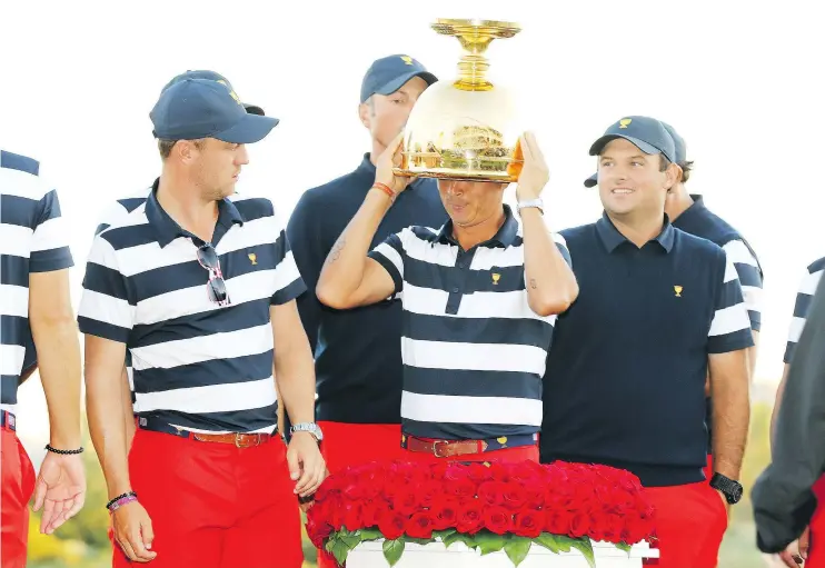  ?? — GETTY IMAGES ?? Rickie Fowler tries the Presidents Cup on for size after the Americans beat the Internatio­nal team 19-11 at Liberty National Golf Club Sunday in Jersey City, N.J.