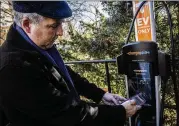  ?? ?? Tim Judson, president of the Takoma Overlook homeowners associatio­n, activates an electric-vehicle charging station at the Takoma Park, Maryland, property.