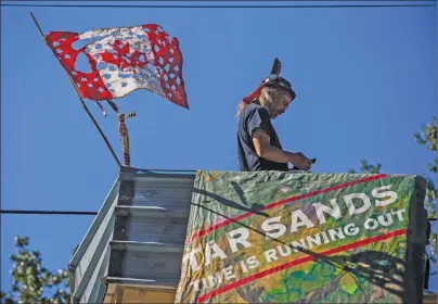  ?? CP PHOTO ?? A man known as Blackwolf stands on top of a structure at Camp Cloud near the entrance of the Kinder Morgan Trans Mountain pipeline facility in Burnaby, B.C.