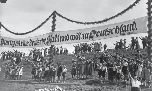  ?? AGENCE FRANCE-PRESSE / FRANCE PRESSE VOIR ?? Des partisans nazis font le salut fasciste, en 1939, sous une bannière écrite en lettres gothiques réclamant le retour de la ville polonaise de Dantzig au sein de l’Allemagne.